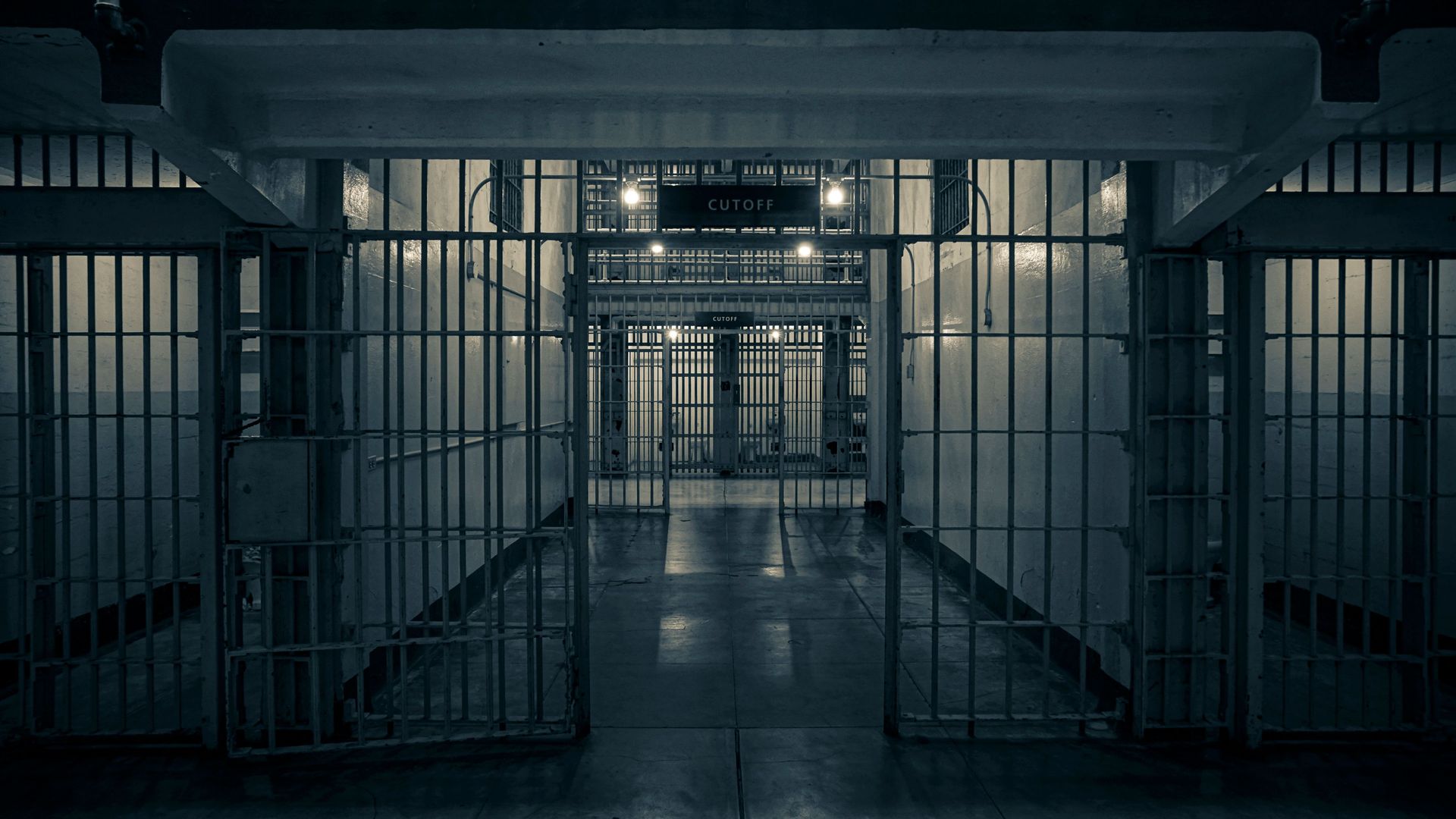 Moody interior of a prison corridor with metal bars, evoking a sense of confinement.